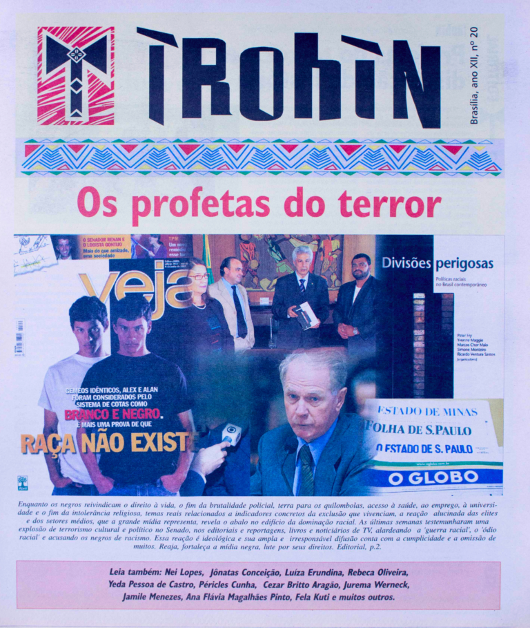 Capa do jornal IROHIN, edição número 20, com o título em destaque “Os profetas do terror” em letras vermelhas. Abaixo, há uma montagem com capas e trechos de jornais e revistas, incluindo a revista Veja com a manchete “Raça não existe”, mostrando gêmeos idênticos, um classificado como branco e o outro como negro. Também há uma imagem de políticos e autoridades reunidos, além de uma foto de um homem sendo entrevistado por jornalistas. No rodapé, um editorial destaca a luta da população negra contra o racismo, a violência policial e a exclusão social. A capa inclui ainda uma lista de colaboradores como Luiza Erundina, Rebeca Oliveira, Yeda Pessoa de Castro, entre outros.